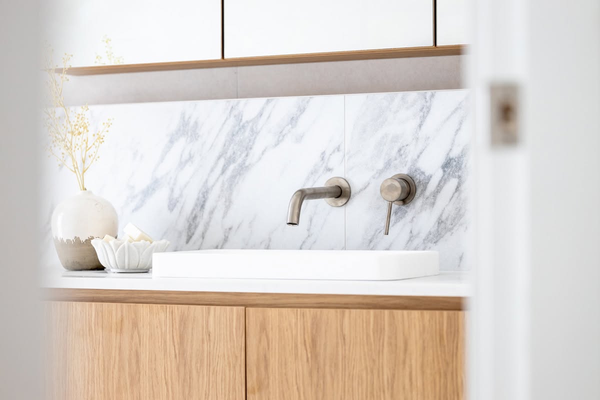 Oak vanity with above-counter basin and marble splashback in a family bathroom