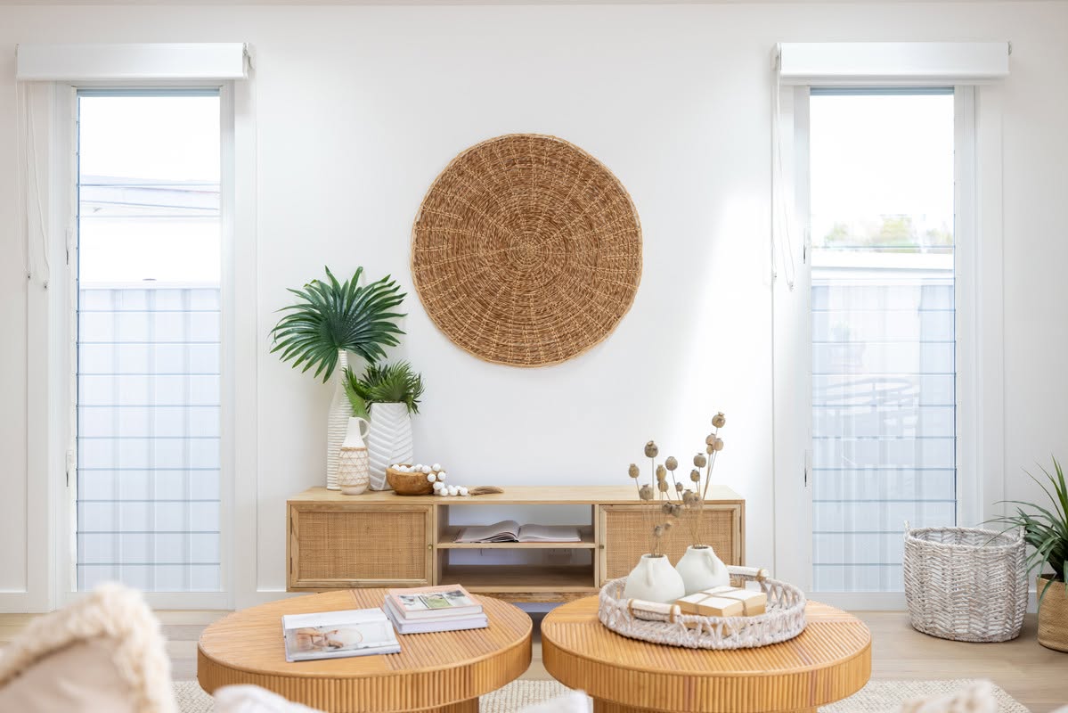 Coastal living room with rattan wall art, timber sideboard and tall glass doors