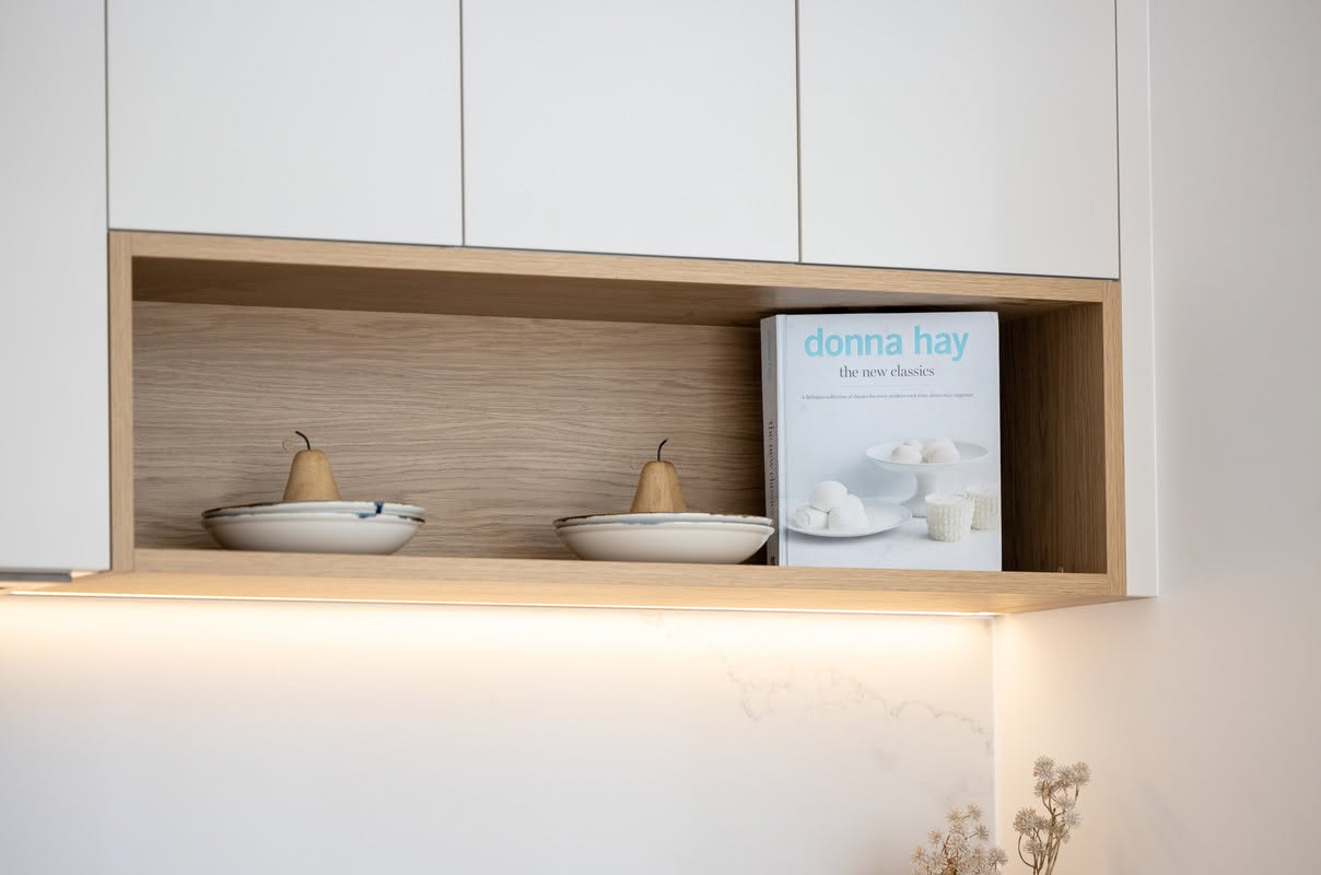 Oak display niche with strip lighting above a stone kitchen benchtop