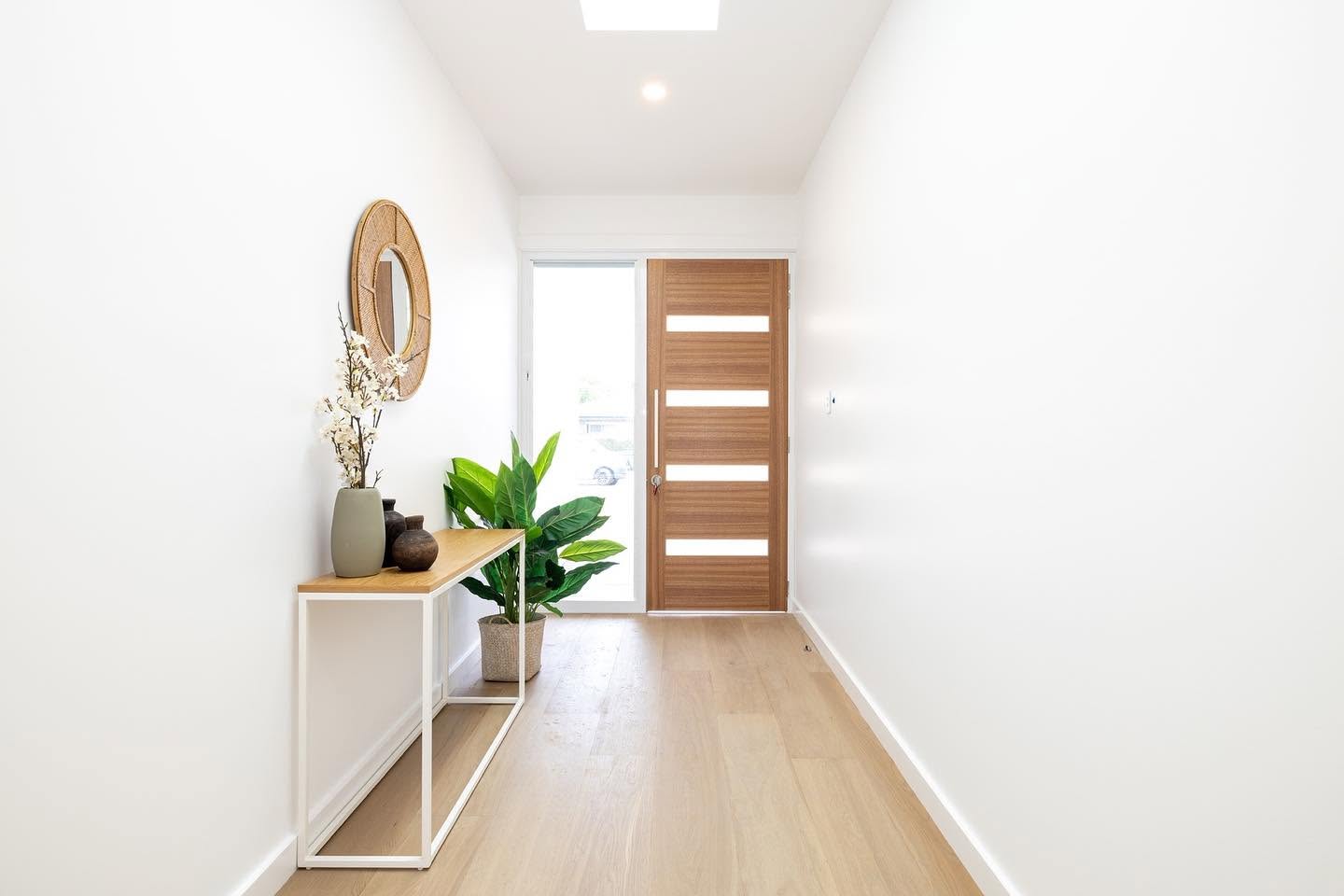 Entry hallway with timber front door, oak flooring and skylight in a Central Coast home