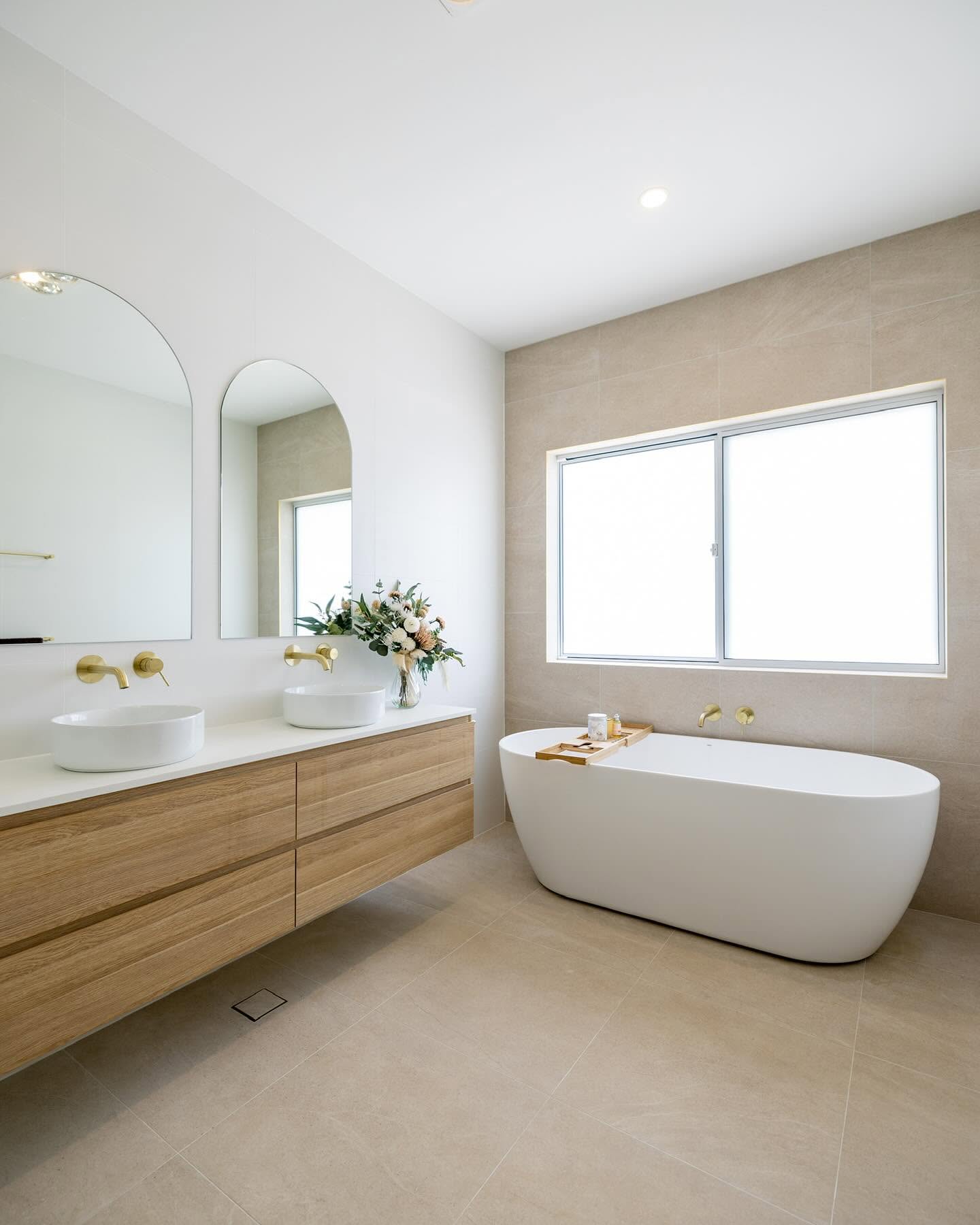 Main bathroom with freestanding bath, twin timber vanity and brushed brass tapware