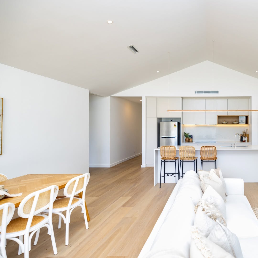 Open plan living and dining looking through to a white kitchen under a raked ceiling
