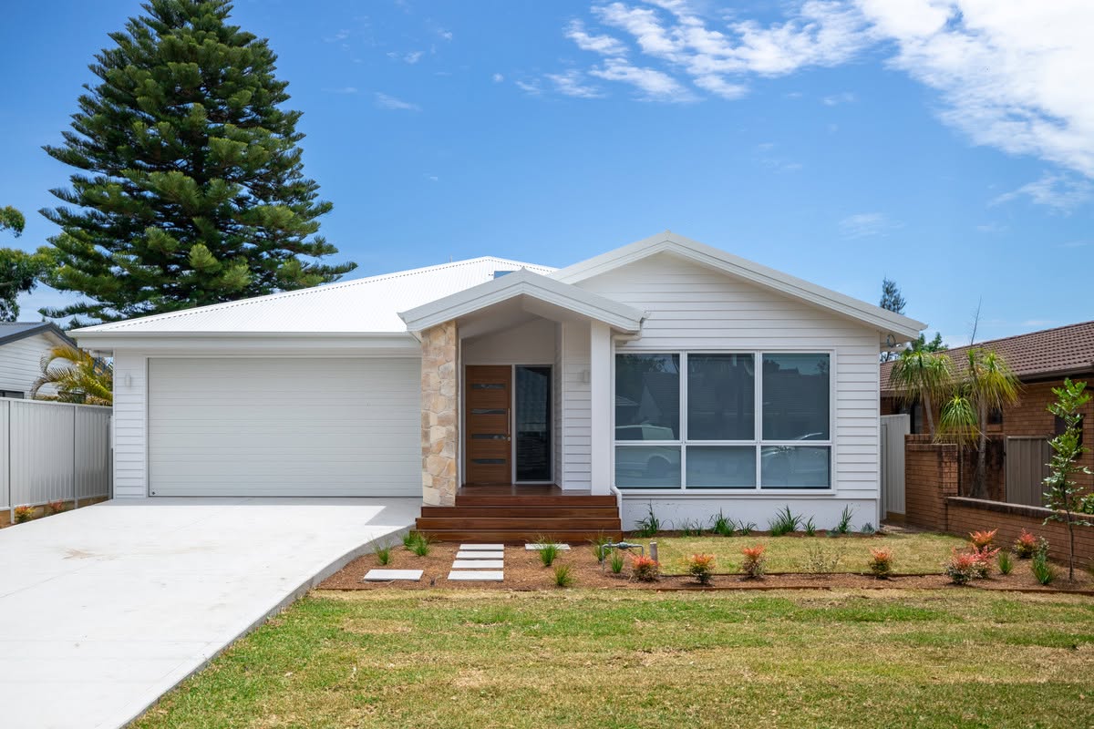 White weatherboard single storey home with stone entry pier and timber deck