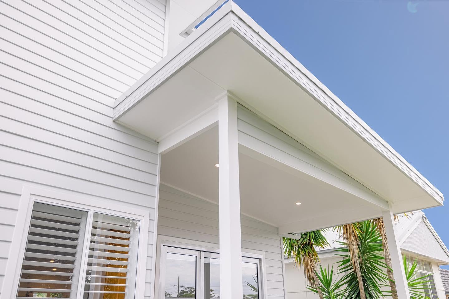 Detail of white weatherboard cladding and a crisp eave on a coastal new build