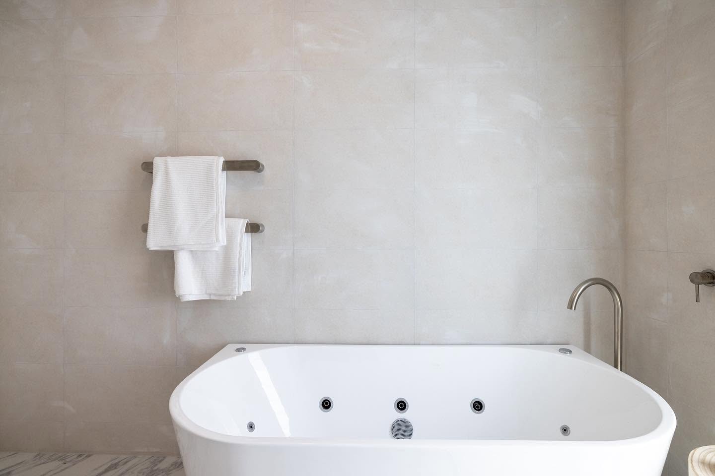 Spa bath and heated towel rail against large format stone look tiles